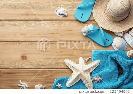 Different seashells with towels and flip flops on brown wooden table Different seashells with towels and flip flops on brown wooden table 123494902