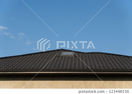 The image captures the sleek roof of a newly constructed house, showcasing a contemporary tiled finish under a clear blue sky, highlighting the architectural beauty The image captures the sleek roof of a newly constructed house, showcasing a contemporary tiled finish under a clear blue sky, highlighting the architectural beauty 123496530