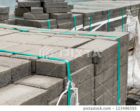 Stacks of cobblestone blocks are organized neatly at a construction site, ready for installation as part of sidewalk development in an urban area 123496593