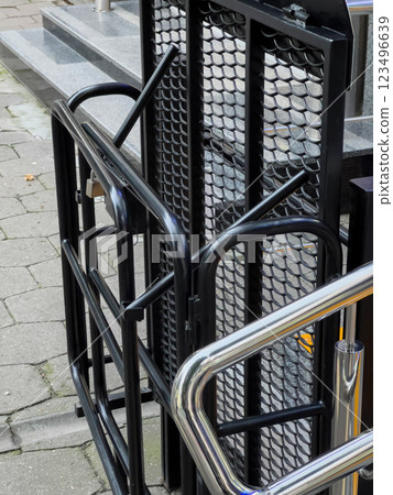 A metallic ramp is installed next to a set of stairs, ensuring accessibility for individuals with mobility challenges in a public area A metallic ramp is installed next to a set of stairs, ensuring accessibility for individuals with mobility challenges in a public area 123496639