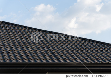 The image features a meticulously tiled rooftop with a modern, durable design. The clean layout of the tiles is highlighted against a backdrop of a clear sky, enhancing its aesthetic appeal The image features a meticulously tiled rooftop with a modern, durable design. The clean layout of the tiles is highlighted against a backdrop of a clear sky, enhancing its aesthetic appeal 123496658