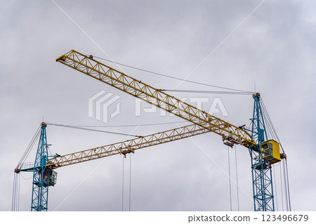 Two large construction cranes tower over a bustling building site, ready to lift heavy materials as workers prepare for an upcoming project on an overcast day Two large construction cranes tower over a bustling building site, ready to lift heavy materials as workers prepare for an upcoming project on an overcast day 123496679