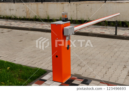 The bright orange barrier arm is installed at a parking lot entrance, designed to manage vehicle entry and enhance security during the daytime 123496693