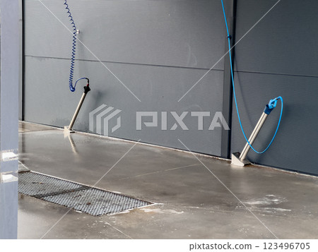 A high-pressure car washing setup features water hoses ready for use, a clean concrete floor, and effective drainage for water runoff during the washing process 123496705