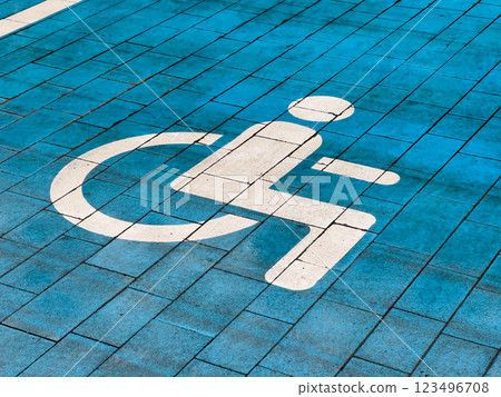 A designated parking spot reserved for disabled individuals features a bright blue paving and a clear accessibility symbol painted in white. This ensures easy identification and access 123496708