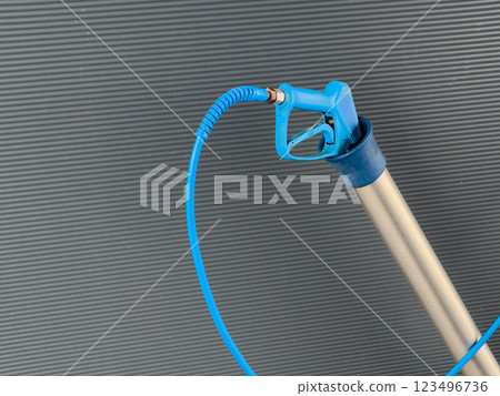 A high-pressure car washer gun with a sturdy nozzle and flexible hose is positioned upright, designed for efficient cleaning of vehicles outdoors A high-pressure car washer gun with a sturdy nozzle and flexible hose is positioned upright, designed for efficient cleaning of vehicles outdoors 123496736