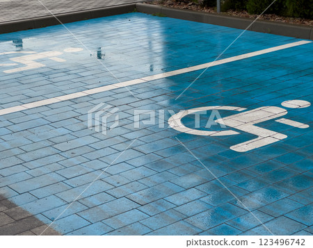 A blue pavement section is marked with a symbol indicating a designated parking spot for disabled individuals, highlighting accessibility in the area 123496742