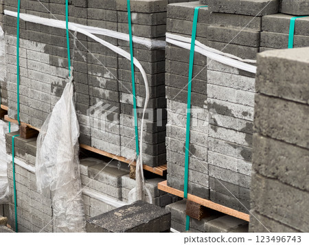 Cobblestones are organized in tall stacks, securely wrapped and prepared for delivery, showcasing their various textures and shades under bright daylight Cobblestones are organized in tall stacks, securely wrapped and prepared for delivery, showcasing their various textures and shades under bright daylight 123496743