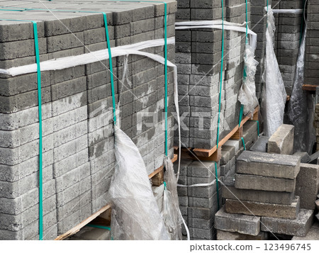 Multiple stacks of gray cobblestones are neatly arranged with plastic wrapping. They are prepared for transport, awaiting use in landscaping or road construction projects Multiple stacks of gray cobblestones are neatly arranged with plastic wrapping. They are prepared for transport, awaiting use in landscaping or road construction projects 123496745