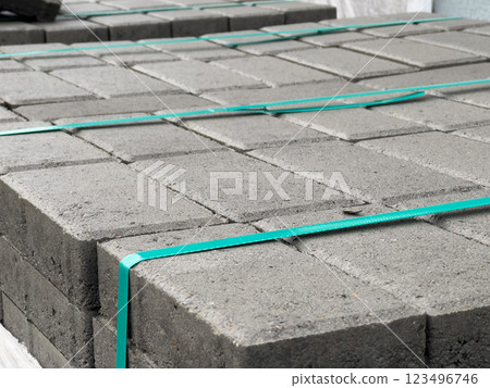 Cobblestones are stacked in neat piles, secured with green straps, awaiting transport for various construction tasks at a storage facility 123496746