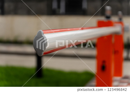A barrier gate stands closed, regulating access to a controlled area in a city environment. The bright colors highlight its purpose for security and management 123496842