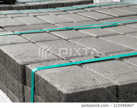 Stacked neatly, gray brick pavers are prepared for sidewalk installation in an urban area, showcasing the materials used in paving projects 123496867