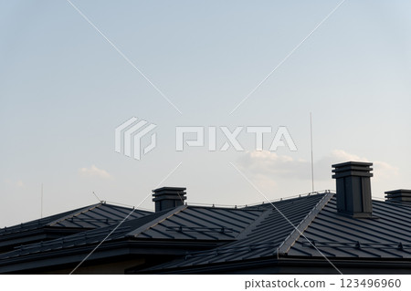 The rooftops of stylish homes rise under a peaceful sky, featuring sleek metal tile designs. These architectural elements reflect the warmth of the afternoon sun The rooftops of stylish homes rise under a peaceful sky, featuring sleek metal tile designs. These architectural elements reflect the warmth of the afternoon sun 123496960