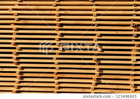 A collection of wooden pallets rests in a well-lit warehouse, their smooth surfaces reflecting the warm afternoon sunlight, creating a beautiful pattern A collection of wooden pallets rests in a well-lit warehouse, their smooth surfaces reflecting the warm afternoon sunlight, creating a beautiful pattern 123496983