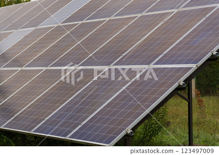 Rows of solar panels glisten in the afternoon light, reflecting the vibrant green surroundings. This clean energy initiative showcases a commitment to sustainability and innovation in technology 123497009