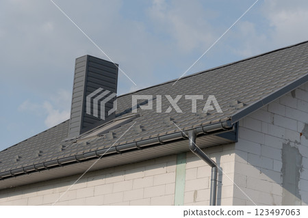 A stylish rooftop highlights contemporary architecture, featuring a prominent chimney and elegant shingles. The bright sky adds a sense of openness and tranquility, enhancing the overall aesthetic A stylish rooftop highlights contemporary architecture, featuring a prominent chimney and elegant shingles. The bright sky adds a sense of openness and tranquility, enhancing the overall aesthetic 123497063