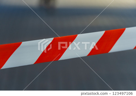 A striking pattern of red and white caution tape stretches across an open area, signaling restricted access while brightly contrasting with the surrounding environment on a sunny day A striking pattern of red and white caution tape stretches across an open area, signaling restricted access while brightly contrasting with the surrounding environment on a sunny day 123497106