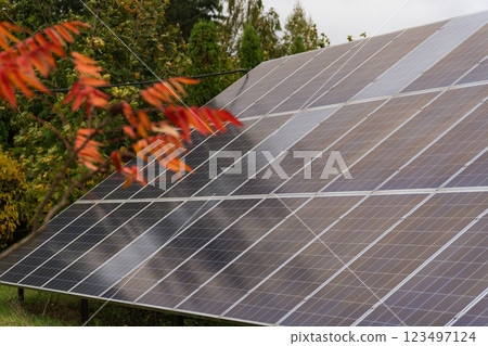 The landscape features glossy solar panels reflecting sunlight amidst vibrant autumn foliage, highlighting a commitment to sustainability in nature's embrace 123497124