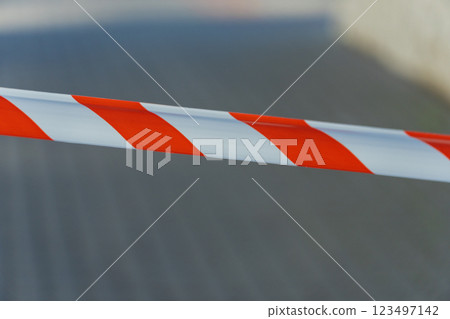 Brightly colored cautionary tape blocks access to a deserted pathway, highlighting a restricted area in an urban environment, illuminated by the midday sun 123497142