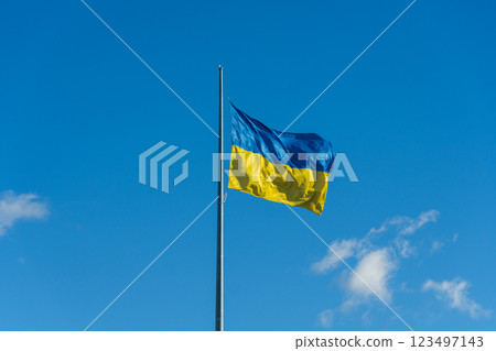 Soaring high above, the blue and yellow flag of Ukraine flutters gently in the crisp air, reflecting the nation's spirit and determination under a clear sky filled with soft clouds Soaring high above, the blue and yellow flag of Ukraine flutters gently in the crisp air, reflecting the nation's spirit and determination under a clear sky filled with soft clouds 123497143