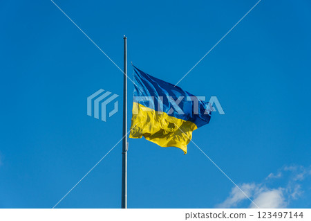 Against the backdrop of a brilliant blue sky, the flag of Ukraine flutters energetically in the breeze, embodying hope and unity amidst challenging times Against the backdrop of a brilliant blue sky, the flag of Ukraine flutters energetically in the breeze, embodying hope and unity amidst challenging times 123497144