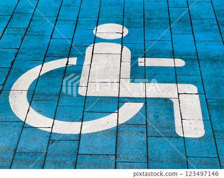 A vibrant blue pavement featuring a clearly defined wheelchair symbol, promoting accessibility for individuals in need. This striking representation enhances public spaces A vibrant blue pavement featuring a clearly defined wheelchair symbol, promoting accessibility for individuals in need. This striking representation enhances public spaces 123497146