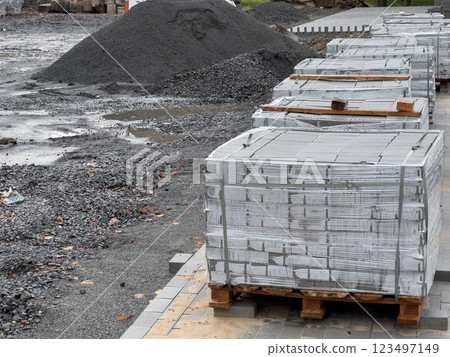 Crates stacked high with gray concrete blocks are neatly arranged on pallets, ready for use in construction at a bustling site in the early hours of the day 123497149