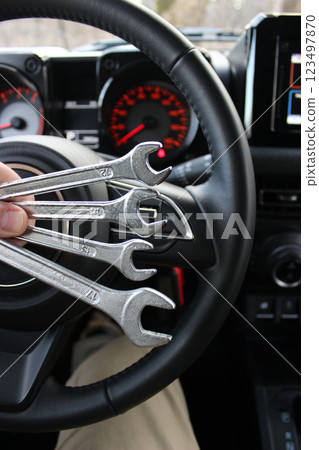 The driver holds in his hands set of spanners for repair in front of the instrument panel inside a car The driver holds in his hands set of spanners for repair in front of the instrument panel inside a car 123497870