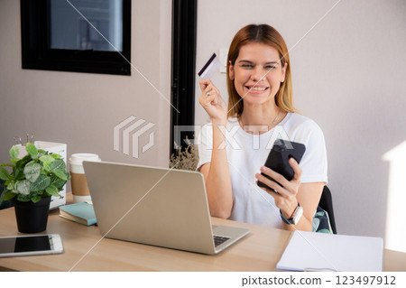 Happy young caucasian woman holding credit card or debit card paying with shopping online. Happy young caucasian woman holding credit card or debit card paying with shopping online. 123497912