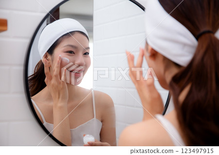 Beautiful young asian woman applying cream or lotion for rejuvenation skin on face. 123497915