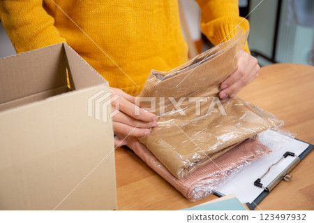 Closeup hand of woman packing in cardboard box for shipping or storage in home office. 123497932