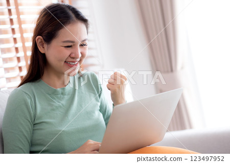 Young asian business woman working with laptop sitting on sofa in home office. Young asian business woman working with laptop sitting on sofa in home office. 123497952