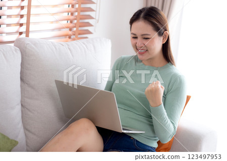 Young asian business woman working with laptop sitting on sofa in home office. Young asian business woman working with laptop sitting on sofa in home office. 123497953