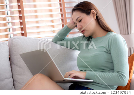 Young asian businesswoman working laptop with stress and frustrated in living room. 123497954