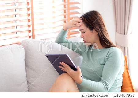 Young asian business woman using tablet computer stress and worried sitting on sofa. Young asian business woman using tablet computer stress and worried sitting on sofa. 123497955