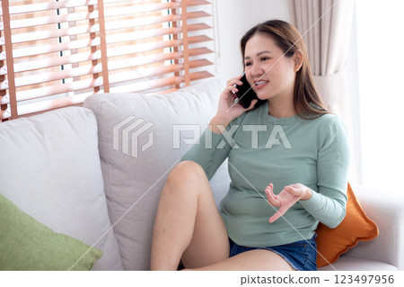 Young asian businesswoman telephone smiling and relax sitting on sofa in living room at home. 123497956