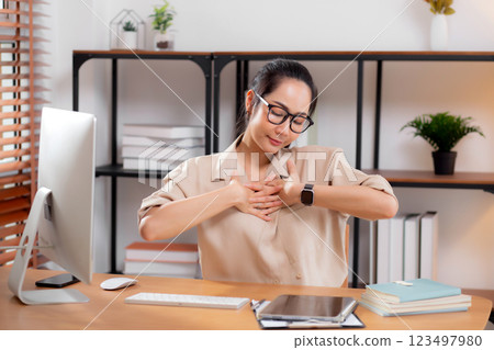 Young asian businesswoman wearing glasses taking a break after overworked with stretching arm. 123497980
