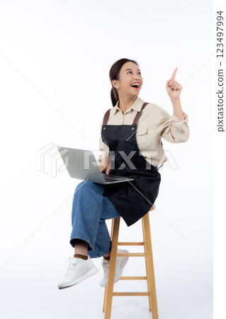 Portrait young asian business woman wearing apron holding laptop computer isolated. 123497994