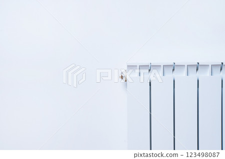 A white radiator mounted on a light wall, showcasing a minimalist design that enhances a clean, modern aesthetic in any space. A white radiator mounted on a light wall, showcasing a minimalist design that enhances a clean, modern aesthetic in any space. 123498087