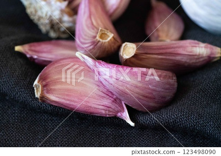 A close-up of vibrant purple garlic cloves resting on a textured black background, showcasing their glossy sheen and natural beauty. 123498090