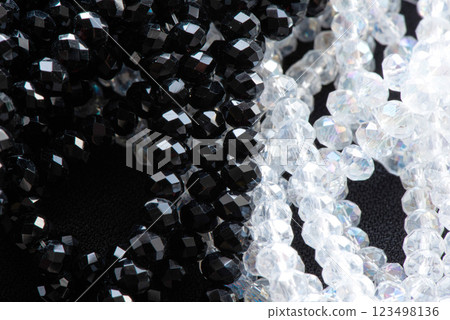 A close-up image showcases a beautiful arrangement of glossy black and crystal-clear beads, highlighting their intricate facets and shine. A close-up image showcases a beautiful arrangement of glossy black and crystal-clear beads, highlighting their intricate facets and shine. 123498136