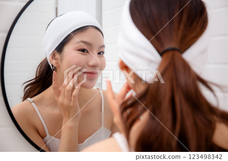 Beautiful young asian woman complexion while looking mirror in bathroom at home. 123498342