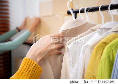 Closeup hand young woman arranging clothes in store for preparation delivery, seller choice clothes. Closeup hand young woman arranging clothes in store for preparation delivery, seller choice clothes. 123498360