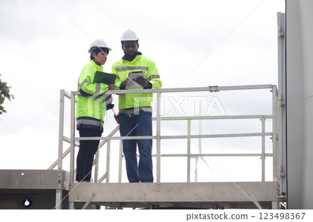 Two engineer check and examining wind turbines in wind farm, renewable energy and teamwork. 123498367