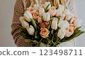A woman holding a bouquet of white and peach flowers 123498711