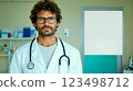 A man in a white lab coat with a stethoscope standing in a hospital room 123498712