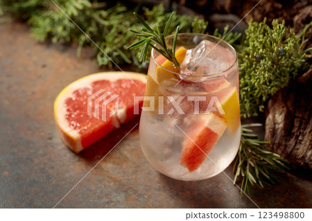 Cocktail: gin and tonic with ice, grapefruit, and rosemary on a rustic background. Cocktail: gin and tonic with ice, grapefruit, and rosemary on a rustic background. 123498800