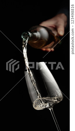 Pouring white wine in a glass. Pouring white wine in a glass. 123498816