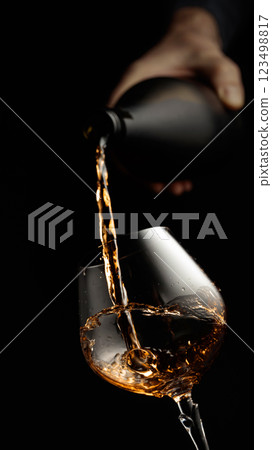 Pouring brandy in a glass goblet. Pouring brandy in a glass goblet. 123498817