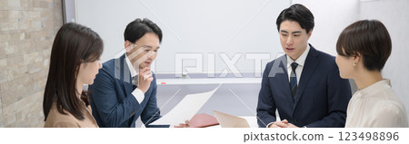A banner showing a meeting of multiple male and female businessmen, discussing and worrying about documents 123498896